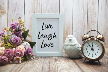 Live Laugh Love text with flower decoration on wooden background