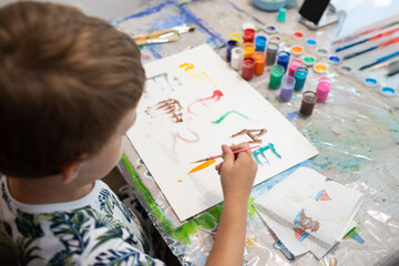 A little boy sits at a table and paints