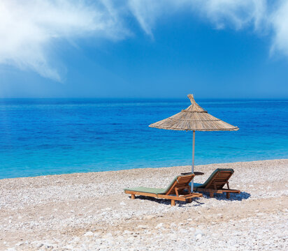 Summer morning sandy beach with sunbeds and strawy sunshade (Albania).