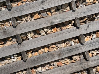 Old wooden railway tracks planks with stones and pebbles as a background