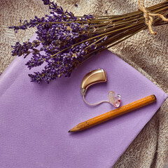BTE hearing aid rests beside a pencil and lavender, symbolizing hearing treatment and creativity in...
