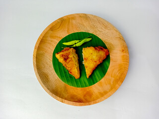 Half of Martabak filled with noodles, savory fried food with green chilies served on a wooden...