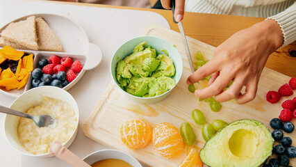 Colorful healthy breakfast with avocado, fruits, and grains on wooden board