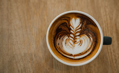 coffee latte art on wood table,A perfectly brewed cappuccino adorned with beautiful latte art, ideal for a morning treat or cafe indulgence.