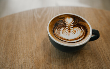 coffee latte art on wood table,A perfectly brewed cappuccino adorned with beautiful latte art, ideal for a morning treat or cafe indulgence.