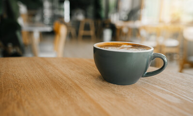 Hot coffee in a cafe with morning sunlight,coffee latte art on wood table