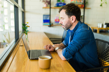 Freelancer working on laptop in coffee shop with coffee
