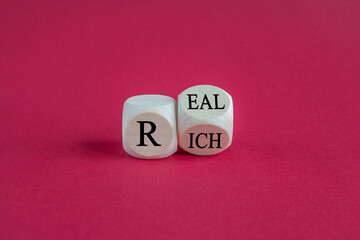 Real rich symbol. Turned a wooden cube with words 'Real rich'. Beautiful red background. Real rich...