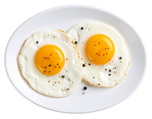 Two sunny side up fried eggs seasoned with black pepper on white ceramic plate, isolated on transparent background PNG