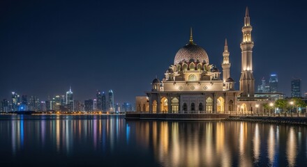 Naklejka premium Beautiful Mosque Lit Up At Night Reflecting In Calm Water With City Skyline In Background