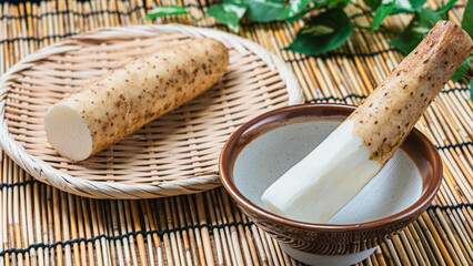 すり鉢に入った長芋と皮付きの長芋を竹ざるにのせた和の食材構成