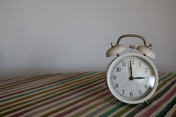 White table bell alarm clock on a colored striped base