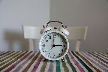White table bell alarm clock on a colored striped base