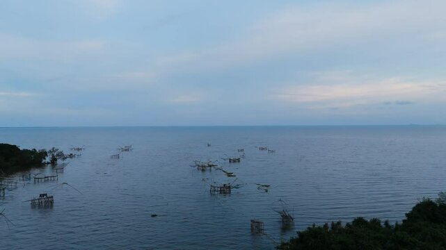 Traditional bamboo fishing nets in a calm lake at dusk. Peaceful rural scene capturing local fishing lifestyle in Southeast Asia. Ideal for travel, nature, and cultural content.