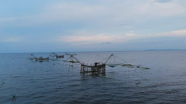 Traditional bamboo fishing nets in a calm lake at dusk. Peaceful rural scene capturing local fishing lifestyle in Southeast Asia. Ideal for travel, nature, and cultural content.