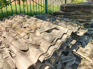 Old gray slate, stacked in uneven piles and broken into pieces of different shapes and sizes. Construction waste after roof repair