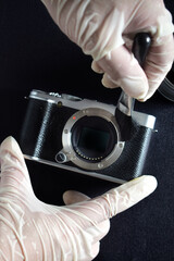 A camera repairman is cleaning the sensor and lens with a brush.