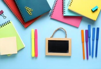 Modern classroom background with stationery essentials, books and supplies ready for the first day of school. Back to school composition with colorful stationery on a desk in front of a chalkboard. 
