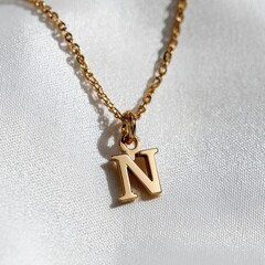 A gold necklace with a small letter n on it