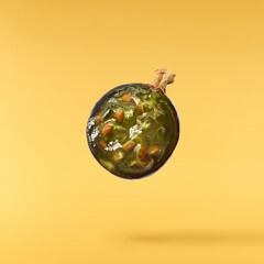 Fresh Ripe Black Currant berries falling in the air isolated on yellow background