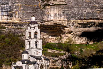 The high tower of the monastery on the background of the mountains.