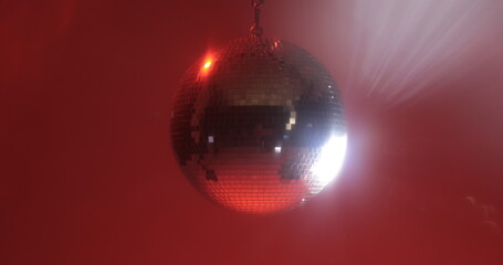 Close-up footage of a spinning disco ball reflecting colorful lights in all directions against a...