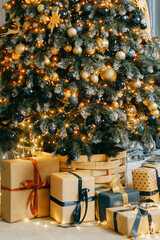 Christmas tree decorated with golden and dark ornaments and warm lights. Festive interior with kraft paper gift boxes under the tree.