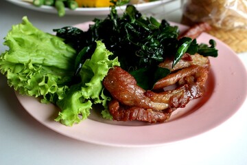 Crispy Thai Fried Pork with Kaffir Lime Leaves and Fresh Lettuce on Pink Plate – Authentic Thai Street Food