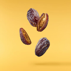 Dried sweet Date fruit falling in the air isolared on yellow background