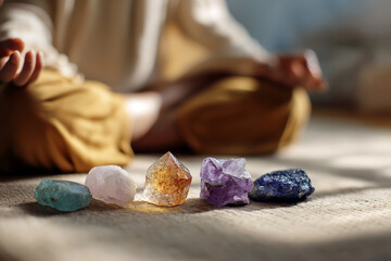 Close-up of colorful healing crystals placed on aligned chakras of a person meditating in lotus pose,  spiritual vibe.