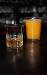 A glass of beer and a shot glass of cognac stand on the bar counter.