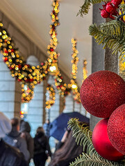 Festive holiday decorations featuring red glitter ornaments and garlands with lights create a warm...