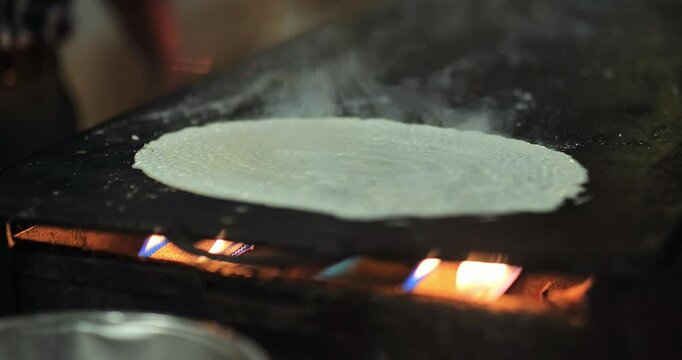 Indian caterers preparing fresh uttapam and crispy dosa on a hot tawa during a live food counter at a festive event