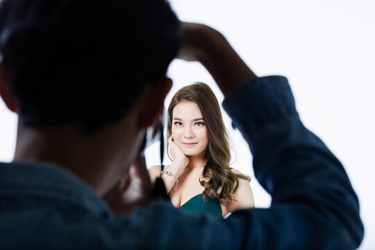 Behind-the-scenes view of female model posing for professional photographer in modern photo studio. Capturing creativity and elegance in fashion photography session.