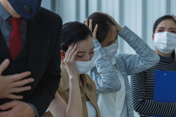 Businesswomen wearing protective face masks showing stress during office meeting, holding their heads in frustration, representing workplace pressure in pandemic situation