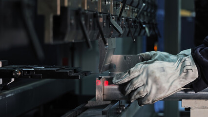 Worker operating CNC press brake machine. Close-up of a worker using a CNC press brake to bend...