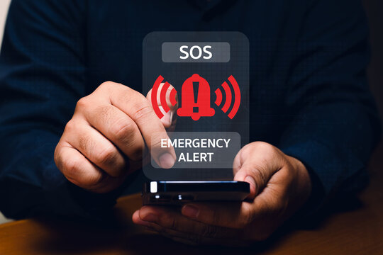 Hands holding a smartphone displaying a holographic emergency alert with SOS and warning symbols.