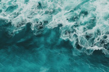 Fototapeta premium Aerial view of turquoise ocean water with white waves creating a soothing natural texture, ideal for backgrounds and nature themed projects