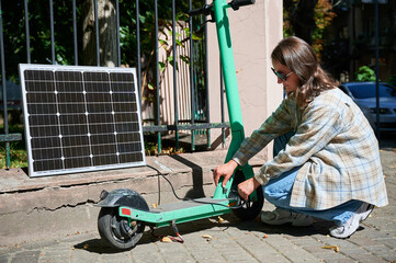 Woman connecting solar panel to electric scooter, highlighting practical application of sustainable...