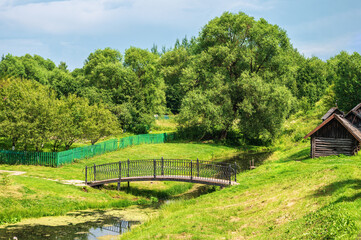 Rural landscape with a small wooden pedestrian bridge over a river.
