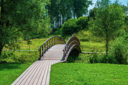 Rural landscape with a small wooden pedestrian bridge over a river.