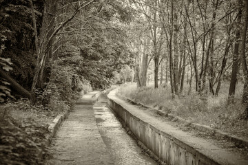 A small river in the city is enclosed in a concrete channel, flows through a beautiful park, the...