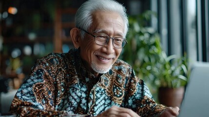 Elderly woman in elegant batik using modern laptop in peaceful indoor space Image 4K UHD