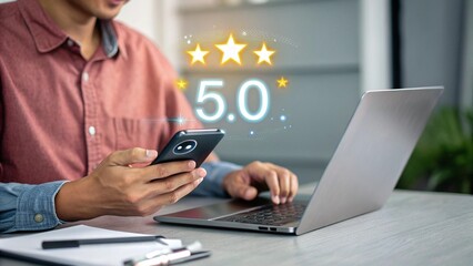 Young Man Reviews Mobile App with Laptop and Smartphone in Office