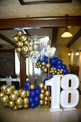 Decoration of blue and yellow balloons. A neon sign that says Happy Birthday in English and a large number eighteen illuminated by LED lights