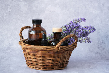 Close up natural beauty product amber glass bottles filled with lavender essential oil in basket with fresh lavender sprigs. Alternative medicine, health and well-being concept.