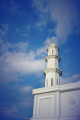 Obraz premium Mosque tower with white clouds in the blue sky