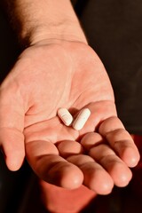 Close-up of male palm with assorted pills. Represents pharmaceutical care and medical treatment.