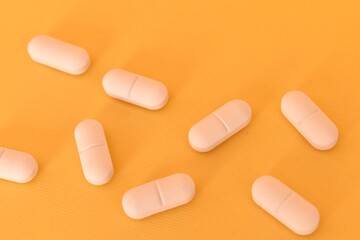 Minimalist photo of white round pills on yellow background. Healthcare, pharmacy, and drug treatment theme.