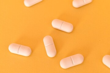 White pills arranged on yellow background. Pharmaceutical concept, treatment and health symbolism.
